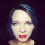 A woman with blue hair and red lipstick advocating for Power to the Plurals.