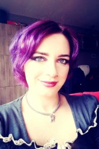 A woman with purple hair, representing The Plural Association, is posing for a picture to raise awareness about OSDD and promote the Power to the Plurals.